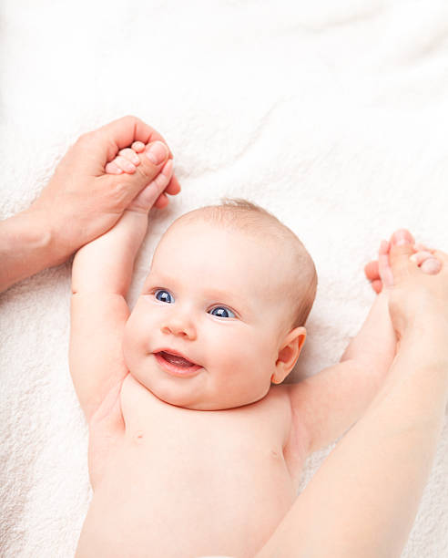 Parent massant doucement les jambes de son bébé pendant un atelier